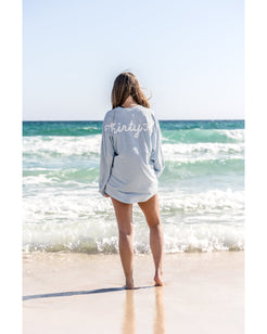 Person wearing a gray sweatshirt with 'thirty' on the beach